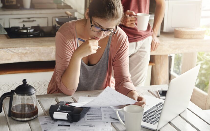 attractive-woman-spectacles-having-serious-concentrated-look-holding-pen-while-filling-papers-calculating-bills-cutting-family-expenses-trying-save-money-make-big-purchase_273609-1686